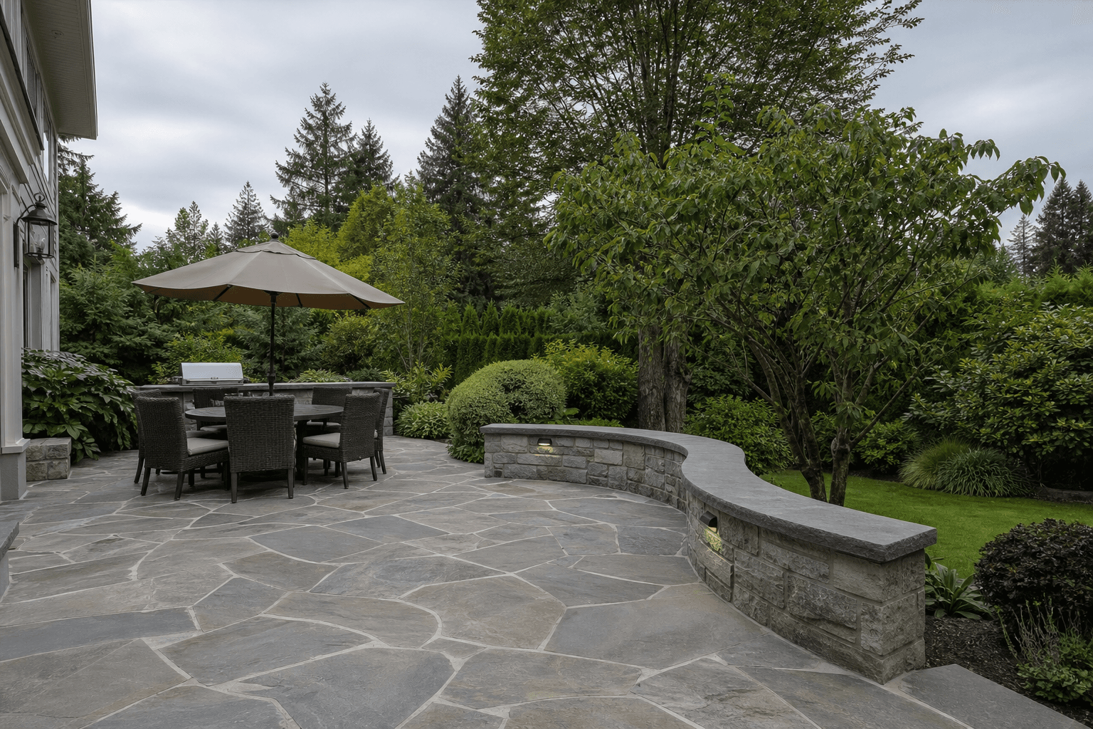 Natural stone patio with low seating wall in a BC backyard
